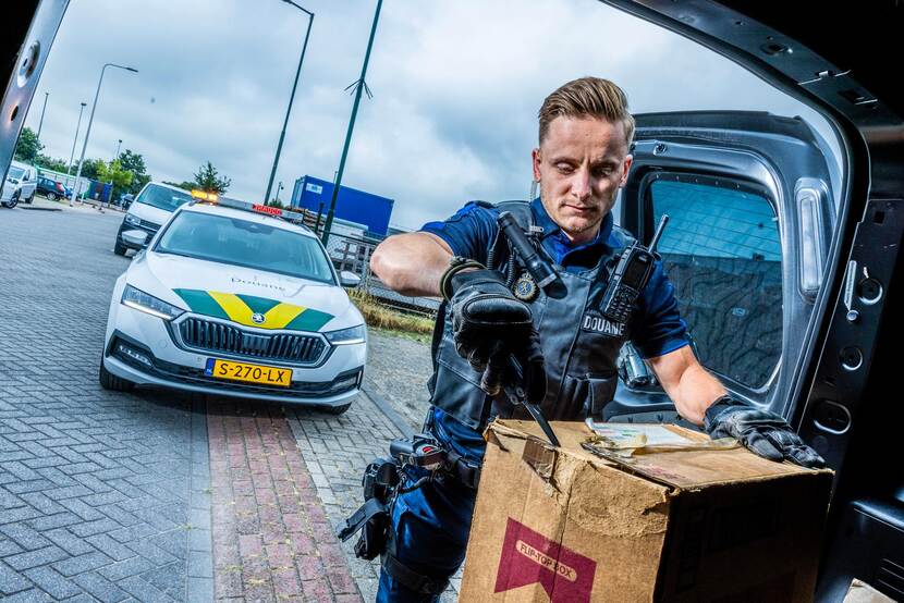 Douanier opent een doos met illegale sigaretten