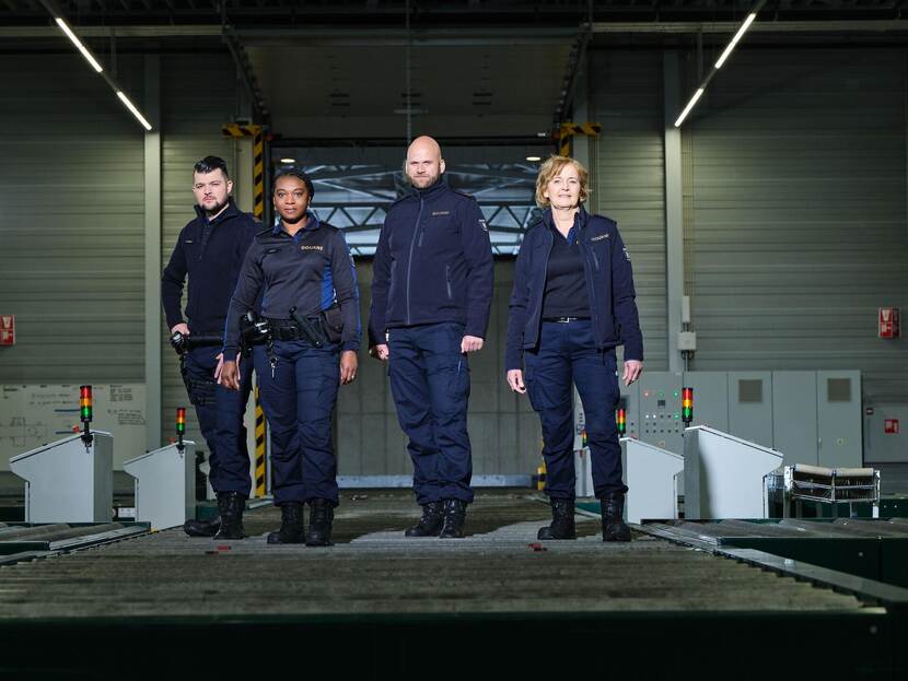 4 douaniers in het uniform van fysiek toezicht: donkerblauw. 4 maal een donkerblauwe cargobroek, 2 maal een fleece vest, 1 maal een trui en 1 maal een polo met lange mouwen