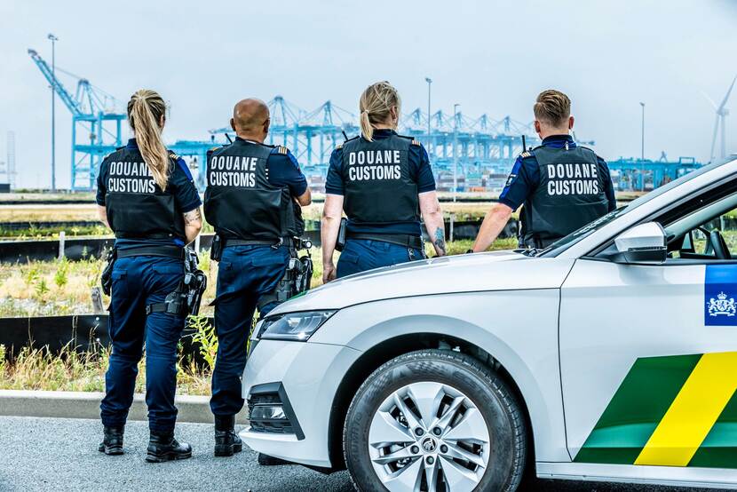 4 douaniers en 1 douanevoertuig. douaniers op de rug gezien