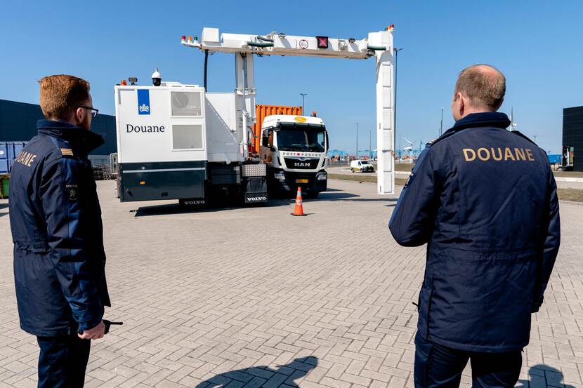 2 douaniers op de rug gezien bij een scan. beiden dragen een donkerblauwe parka